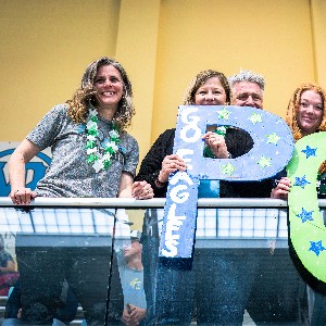 Pine Creek Swim Parents holding up oversized letters that say PC for Pine Creek and, "Go, Eagles"